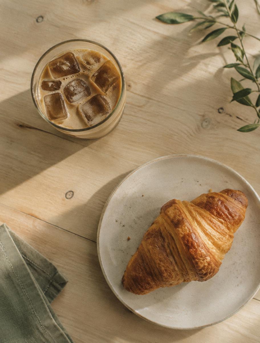 Iced coffee and a croissant on a wooden table